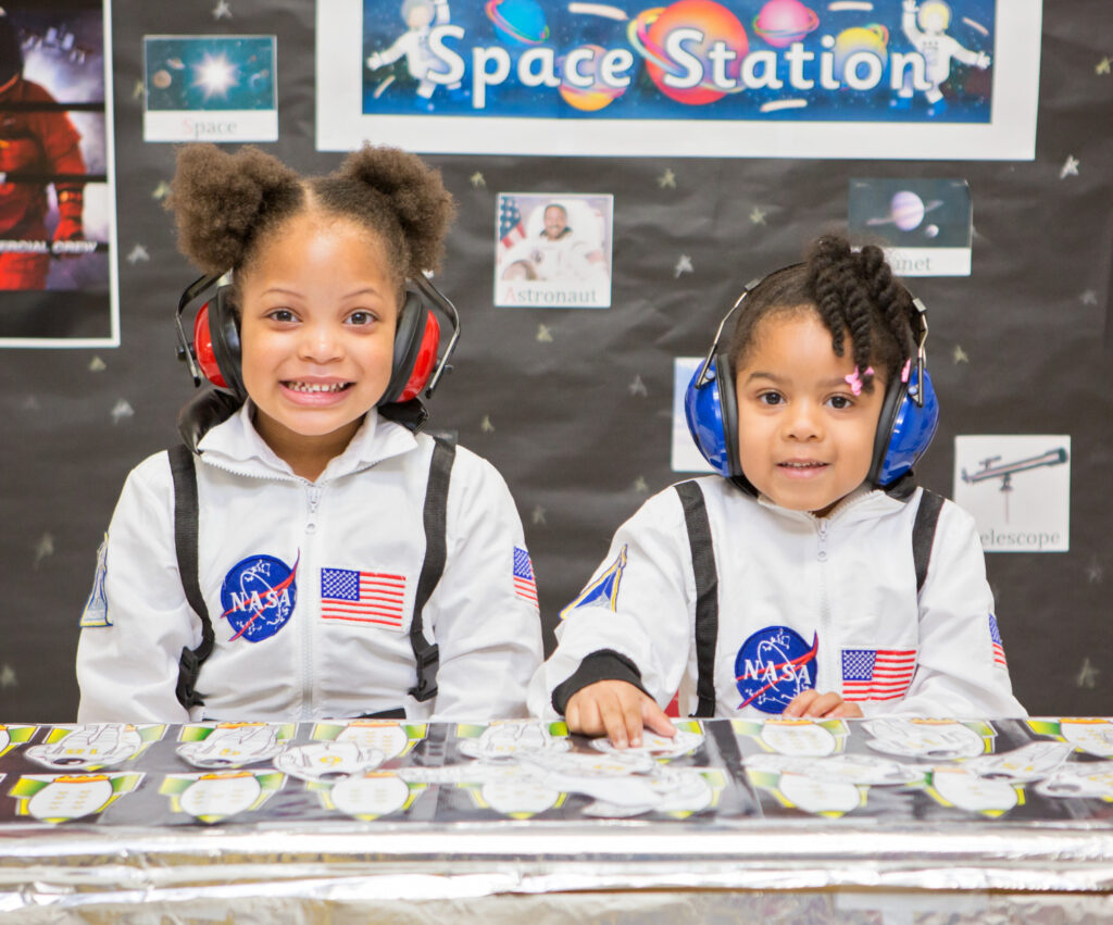 Two smiling young girls dressed as astronauts